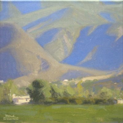 Ojai Mountain Shadows, giclee print by Dan Schultz. Large mountains with blue and violet shadows rise behind a green foreground.